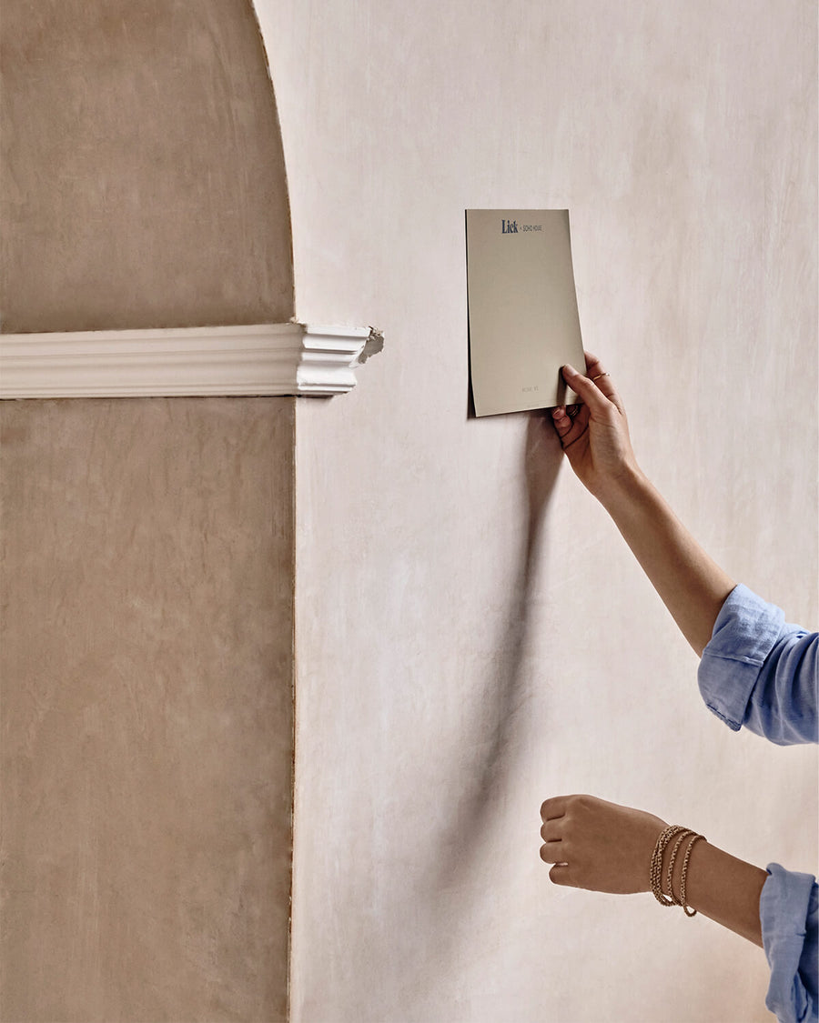 Image of a person applying a Lick Beige 02 Soho Farmhouse peel-and-stick sample to a wall